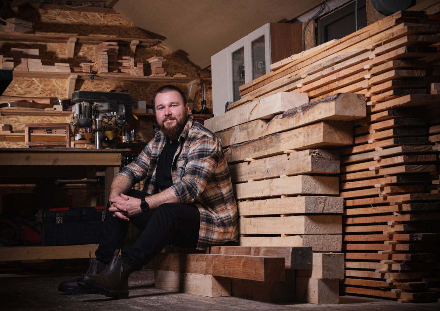 Mario sitting among stacks of wooden planks in a workshop.